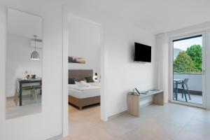 a white room with a bedroom and a bed and a window at Bike Apartments Curti - Waldgrün in Laives