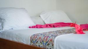 a white bed with pink sheets and pillows at Ampasoa Beach in Nosy Be