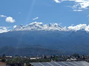 a snow covered mountain in front of a city at Terraza Amecameca in Amecameca de Juárez +3 photos