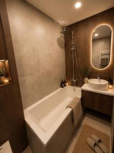 a bathroom with a tub and a sink and a mirror at Luxury apartment in Vilnius