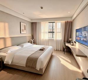 a bedroom with a large bed and a flat screen tv at Yiwu Bai Heng Hotel in Yiwu