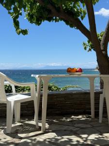 a white table and two chairs and the ocean at EverBlue Suites - Halkidiki Beachfront in Psakoudia +42 photos