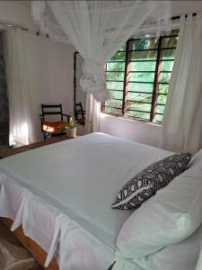 a bedroom with a large white bed with a window at The Nook,Kilifi in Kilifi +5 photos
