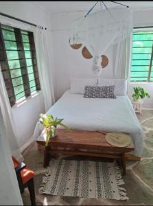 a bedroom with a white bed with a wooden table at The Nook,Kilifi in Kilifi