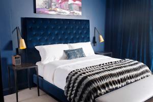 a blue bedroom with a large bed with a blue headboard at Hotel Covington Cincinnati Riverfront in Covington
