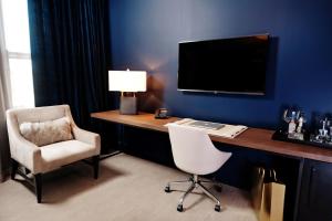 a room with a desk with a chair and a television at Hotel Covington Cincinnati Riverfront in Covington