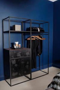 a black rack with clothes on it against a blue wall at Hotel Covington Cincinnati Riverfront in Covington