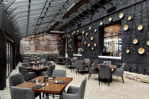a restaurant with tables and chairs and a brick wall at Hotel Covington Cincinnati Riverfront in Covington