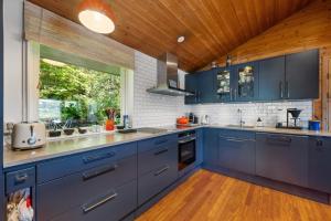 a kitchen with blue cabinets and a wooden ceiling at Skyline View - Nordic Villa Above Bergen in Bergen