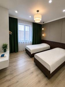 two beds in a room with green curtains at Souluna lodge in Chyrpykty
