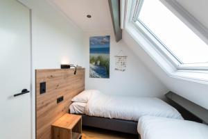 a bedroom with two beds and a window at Friese Antillen in Hollum