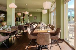 a dining room with tables and chairs and windows at Dormio Hotel Der Seehof in Heimbach