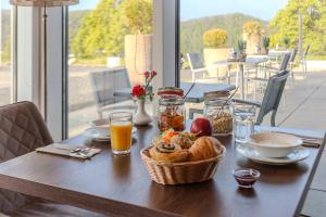 a table with a basket of bread and a basket of orange juice at Dormio Hotel Der Seehof in Heimbach +22 photos