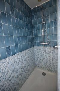 a blue tiled bathroom with a tub with a shower at La Chandeler in Juvigny-sous-Andaine +7 photos