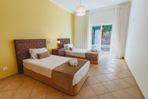 a bedroom with two beds and a chair and a window at Villa Belchior by Algarve Holidays in Faro +30 photos
