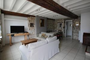 a living room with two white couches and a tv at La Chandeler in Juvigny-sous-Andaine