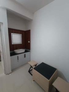 a bathroom with a sink and a table and a chair at Kalpaka lee divine in Guruvāyūr
