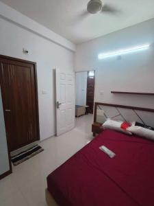 a bedroom with a red bed and a door at Kalpaka lee divine in Guruvāyūr