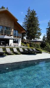 a house with chairs and a swimming pool in front of it at Gogodz Chalet Resort in Yablunytsya