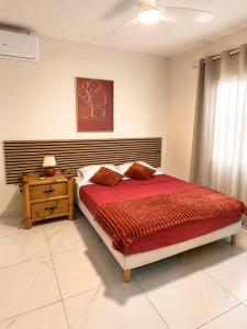 a bedroom with a large bed and a wooden nightstand at VILLA CARAIBE in Sainte-Luce