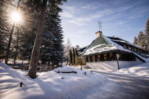 a building covered in snow with the sun behind it at Chalet Evergreen in Borovets