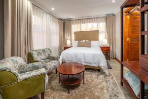 a hotel room with a bed and a chair and a table at 36 Alexander Guesthouse,Highlands,Harare in Highlands