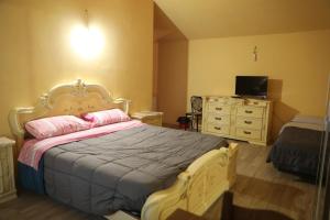 a bedroom with a bed and a dresser and a television at Cusna Rooms in Febbio