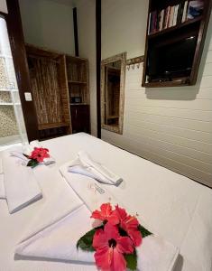 a white table with red flowers on top of it at Pousada Naiepe in Fernando de Noronha