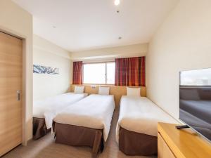 a hotel room with four beds and a tv at Hotel Keihan Kyobashi Grande in Osaka