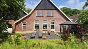 a red brick house with a gazebo in front of it at Landhuis onder de lindeboom in Losser