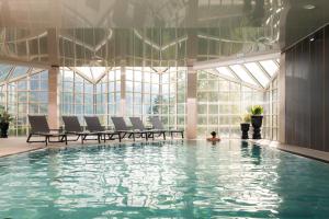 a pool with chairs and a person in the water at MONDI Chalets am Grundlsee in Grundlsee