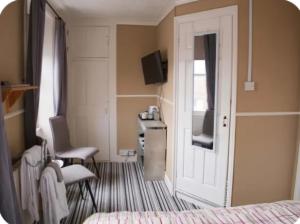 a room with a bed and a desk and a door at Trillberry Guesthouse in Weymouth