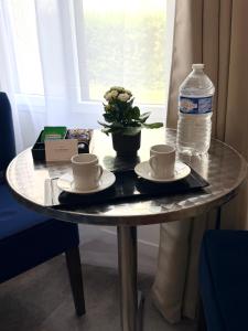 a table with two cups and a bottle of water at Aux Charmes - Suites Prestige et Petit Déjeuner en chambre - Cote d Opale in Isques