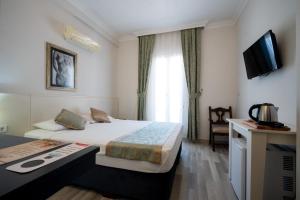 a hotel room with a bed and a television at Artemis Hotel in Bodrum City
