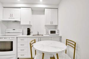 a kitchen with white cabinets and a white table and chairs at Elegance comfort à Montreal in Montreal