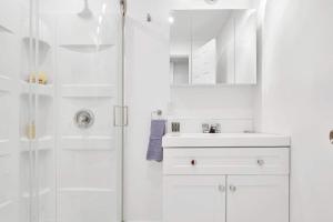 a white bathroom with a shower and a sink at Elegance comfort à Montreal in Montreal
