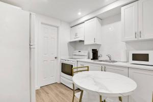 a kitchen with white cabinets and a white table at Elegance comfort à Montreal in Montreal