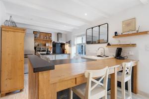 a kitchen with a large wooden counter with two white chairs at Ti Illiz in Le Conquet