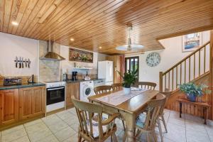 a kitchen with a wooden ceiling and a table and chairs at La Poya in Plonévez-du-Faou