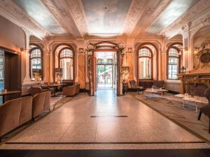an ornate room with a lobby with chairs and a fireplace at Royal St. Georges Hotel Interlaken - MGallery Collection in Interlaken