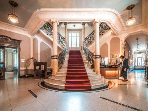 a man walking down a staircase in a building at Royal St. Georges Hotel Interlaken - MGallery Collection in Interlaken