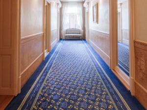 a hallway with a blue carpet and a chair at Royal St. Georges Hotel Interlaken - MGallery Collection in Interlaken +196 photos