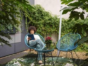 a woman sitting in a chair with a book at Aparthotel Adagio Access Paris Reuilly in Paris
