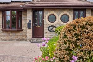 a brick house with a brown door and some flowers at Host & Stay - Puffin Cove in Seahouses