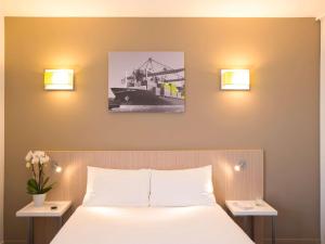 a bedroom with a bed and two lights on the wall at Aparthotel Adagio Access Le Havre Les Docks in Le Havre