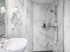a white bathroom with a shower and a sink at ibis Styles Amsterdam Amstel in Amsterdam +58 photos