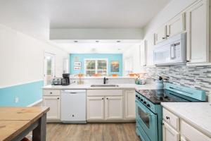 a kitchen with white cabinets and blue appliances at Pool & Spa Game Rm Walking Distance to Beach & Shops in Duck