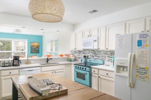 a kitchen with white cabinets and blue appliances at Pool & Spa Game Rm Walking Distance to Beach & Shops in Duck
