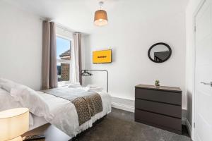 a bedroom with a bed and a mirror and a window at Large 6-Bed House - 5 Bathrooms w Free Parking by StaySejour in Sompting