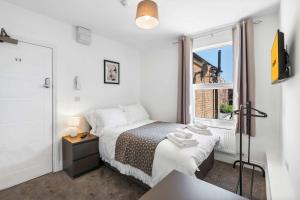 a small bedroom with a bed and a window at Large 6-Bed House - 5 Bathrooms w Free Parking by StaySejour in Sompting